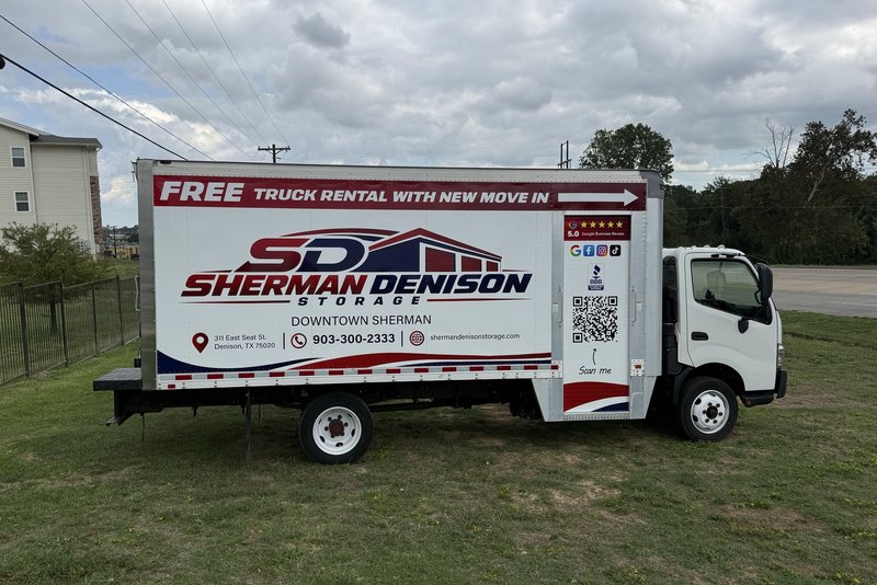 White box truck reading Free Truck Rental With New Move In parked beside a lawn