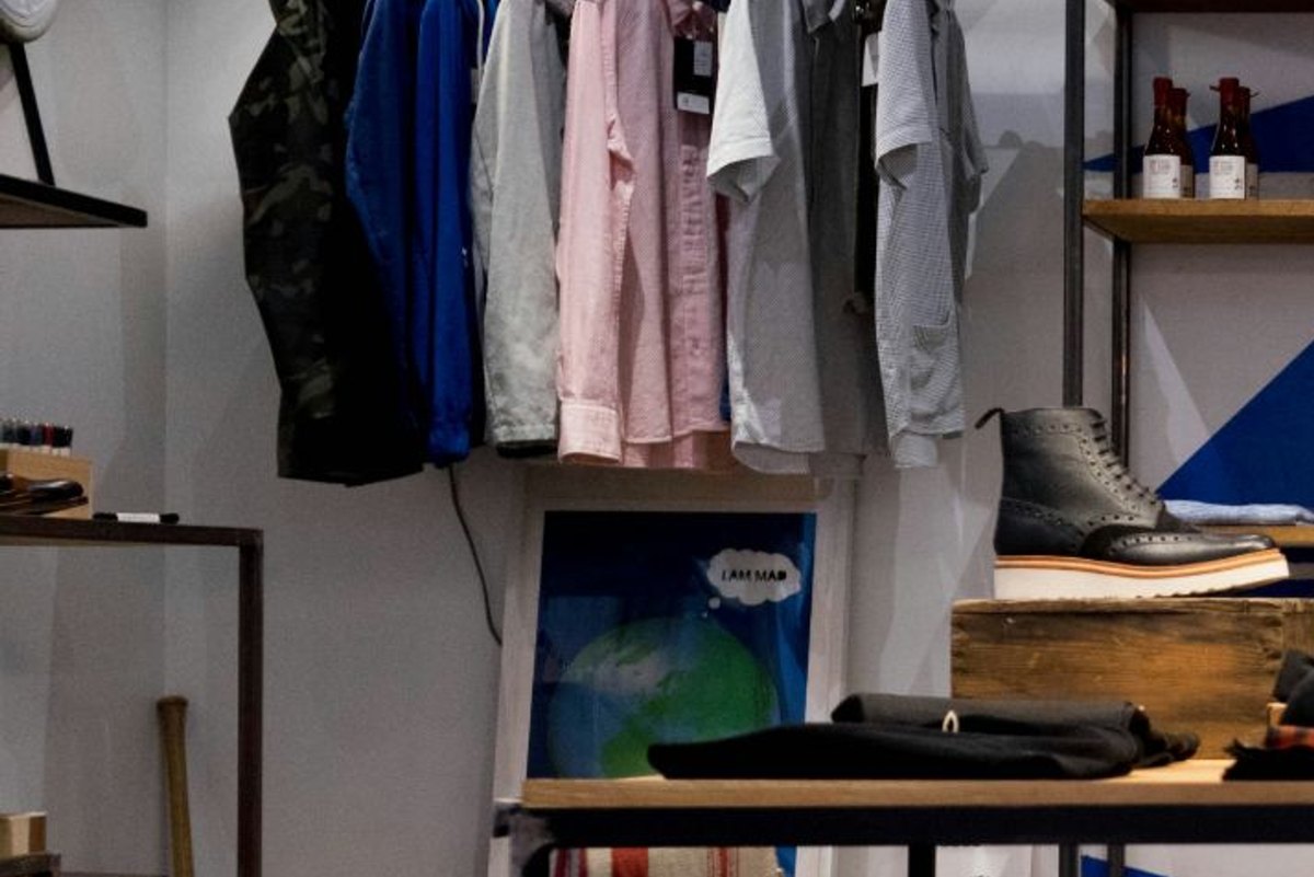 Shirts and jackets hanging on a pipe clothing rack in a small shop
