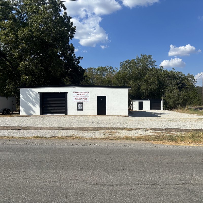 Straight-on view of the white block storage building across a street, with a smaller building beside it